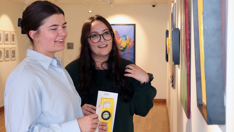 USU undergrad scholars Ella White, left, and Kjrstine Landaverde curated and installed the Latinx Art Exhibition 2026 at downtown Logan's ReadyMade Gallery. The exhibition is Sept. 9 through Oct. 3, with a public reception Sept. 12, during Cache Valley’s Gran Latino Festival. (Photo credit: USU/M. Muffoletto)