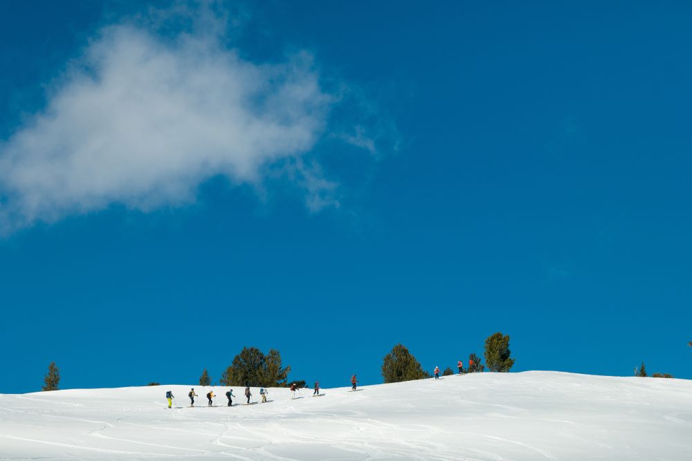 big blue sky with snowy hill and skiers