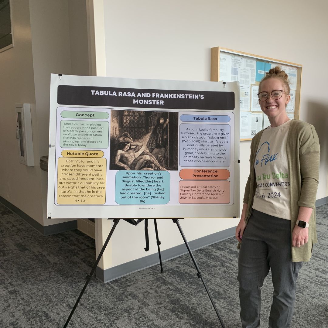 Dakota Mecham standing in front of reserch presentation boards.