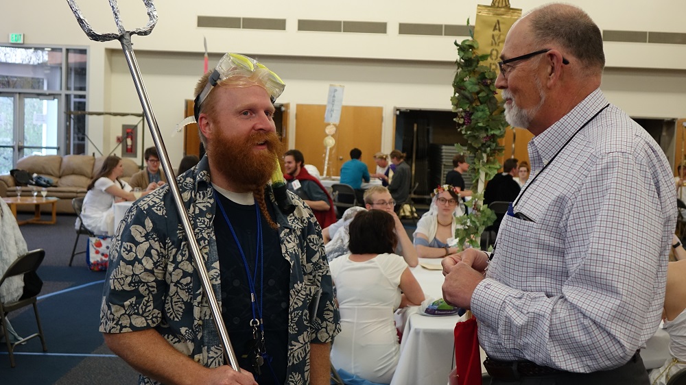 man dressed as greek god speaks to another man