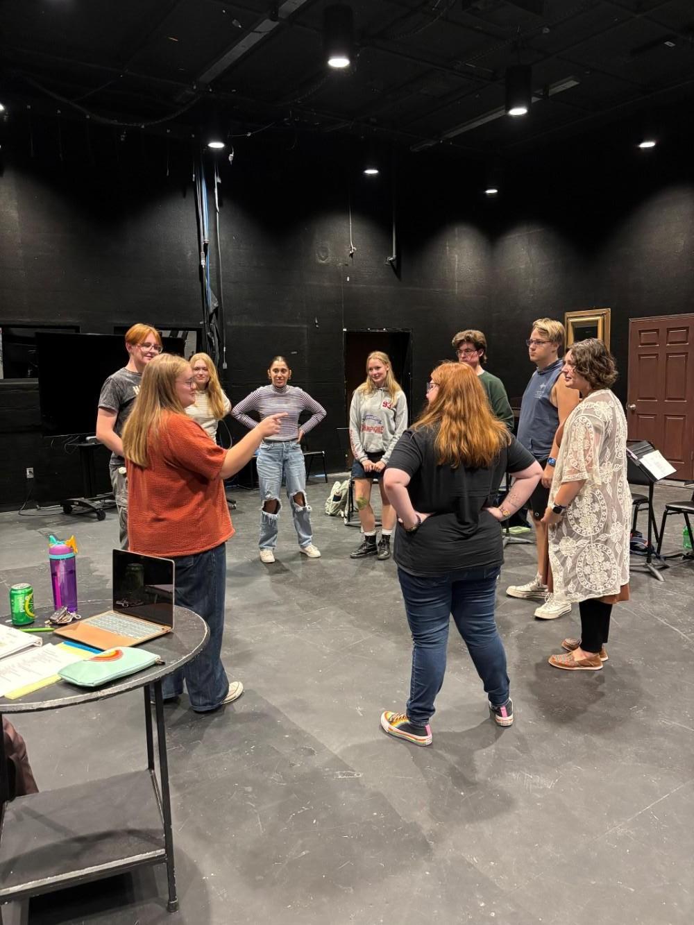 A group of cast members stand in a circle, participating in a group activity.