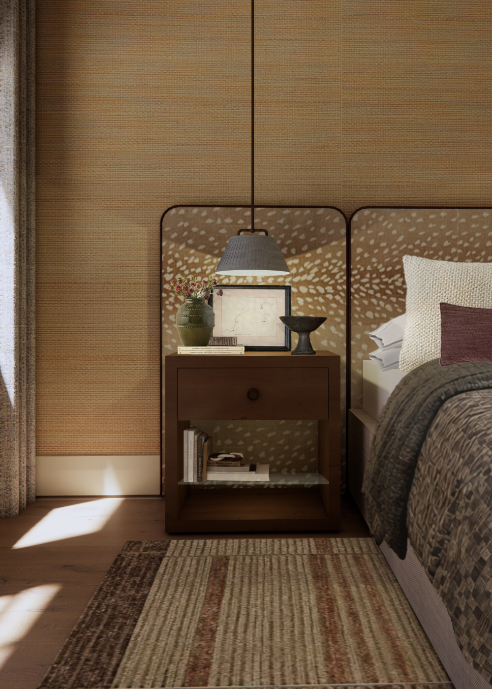 A primary bedroom vignette features a wooden nightstand styled with a green vase of flowers and a framed sketch against a textured grasscloth wallpaper. A low-hanging pendant lamp illuminates the space, which includes a bed with a patterned headboard and a woven striped rug on the wood floor.