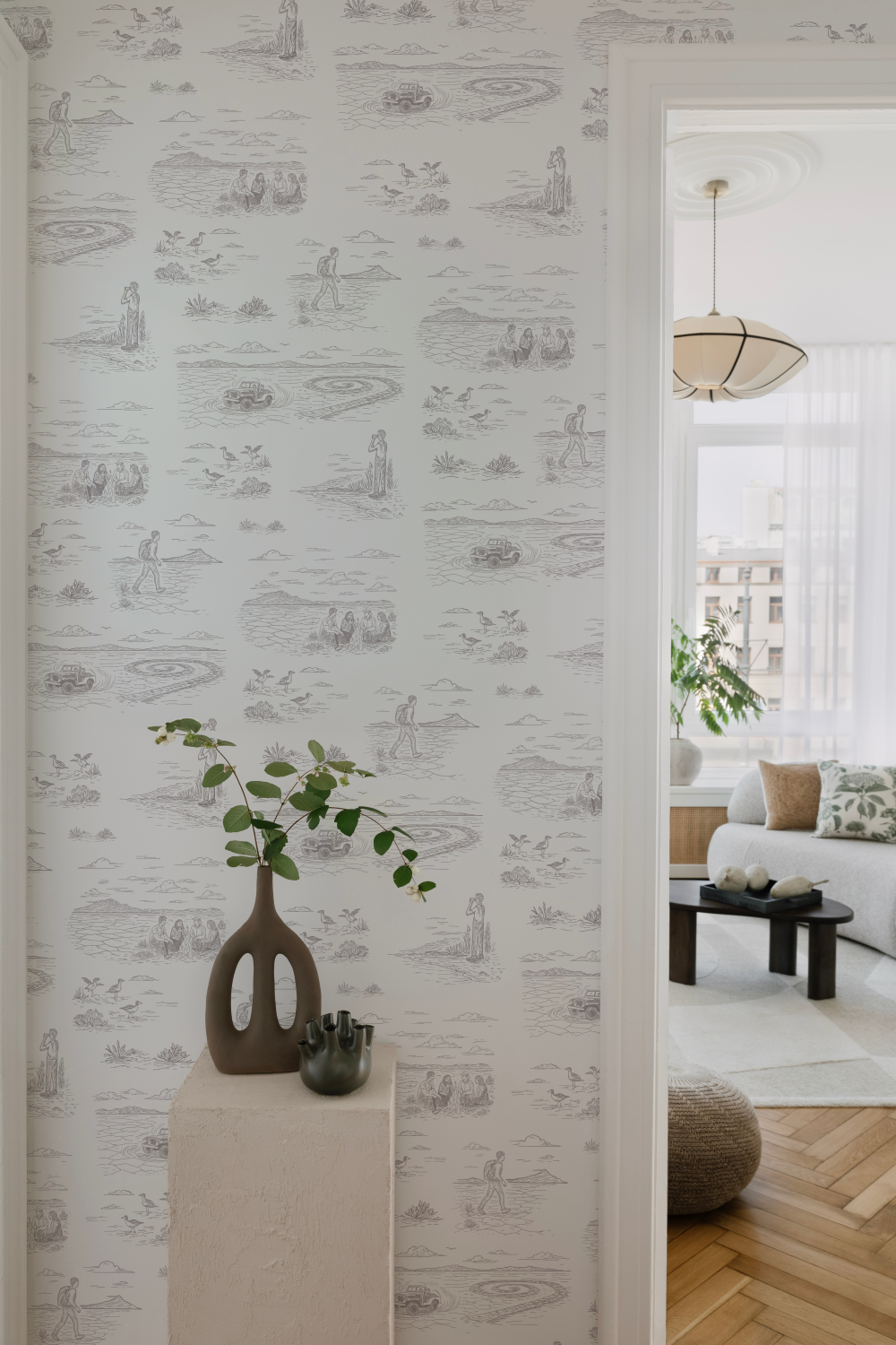 A vignette with a vase on a pedestal with a dusty purple and white wallpaper behind it
featuring images of the Bonneville Salt Flats, the Spiral Jetty, and people recreating.
