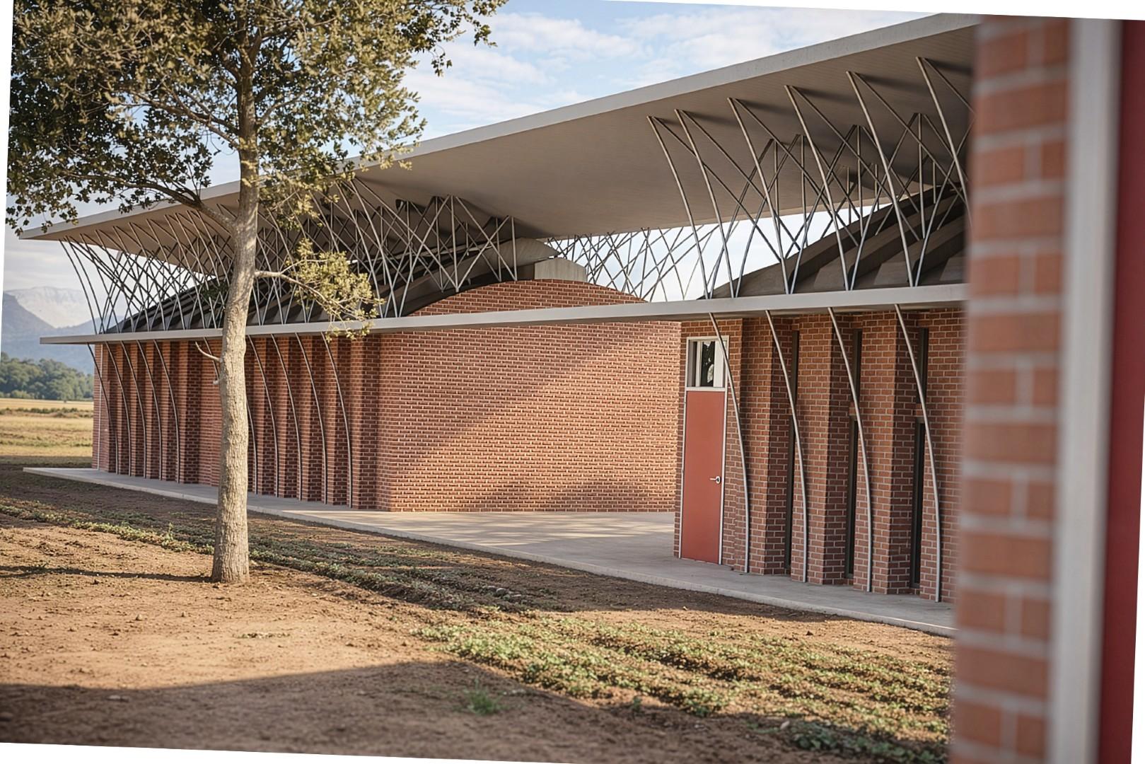 Brick building with vertical steel supports and a large overhanging roof, set in a rural
landscape with a tree in the foreground.