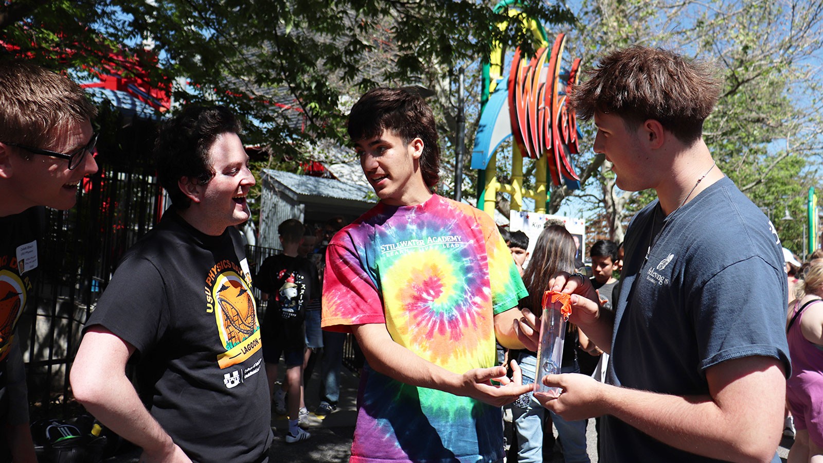From left, USU student volunteers Caleb Black and Gabriel Decker discuss measurement of G-forces on a roller coaster with high school students from Stillwater Academy in South Jordan, Utah, who display an accelerometer they built themselves. The scholars were participating in USU Physics Day at Lagoon on May 15 at the Northern Utah amusement park.