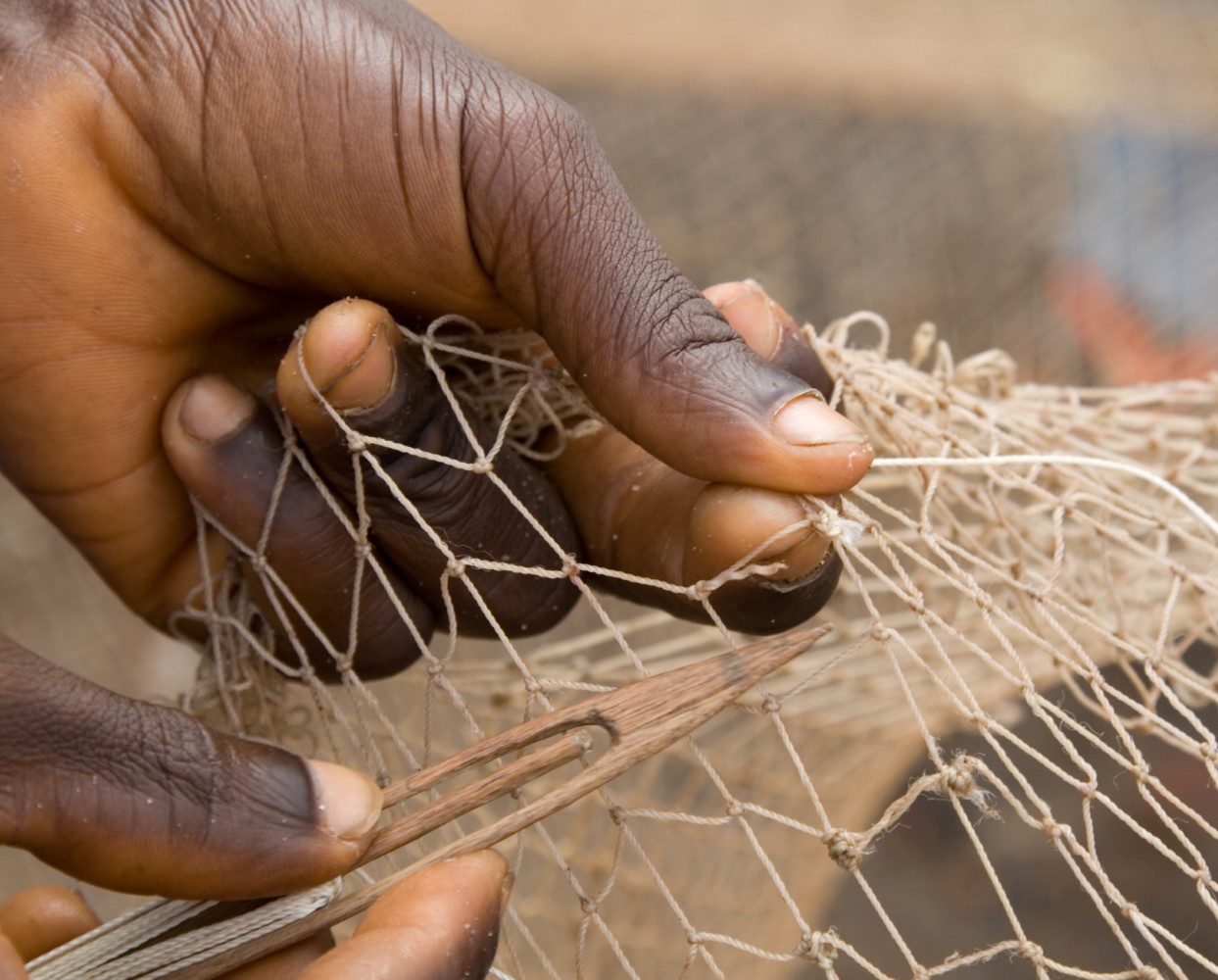 A fishing net being repaired by hand.
