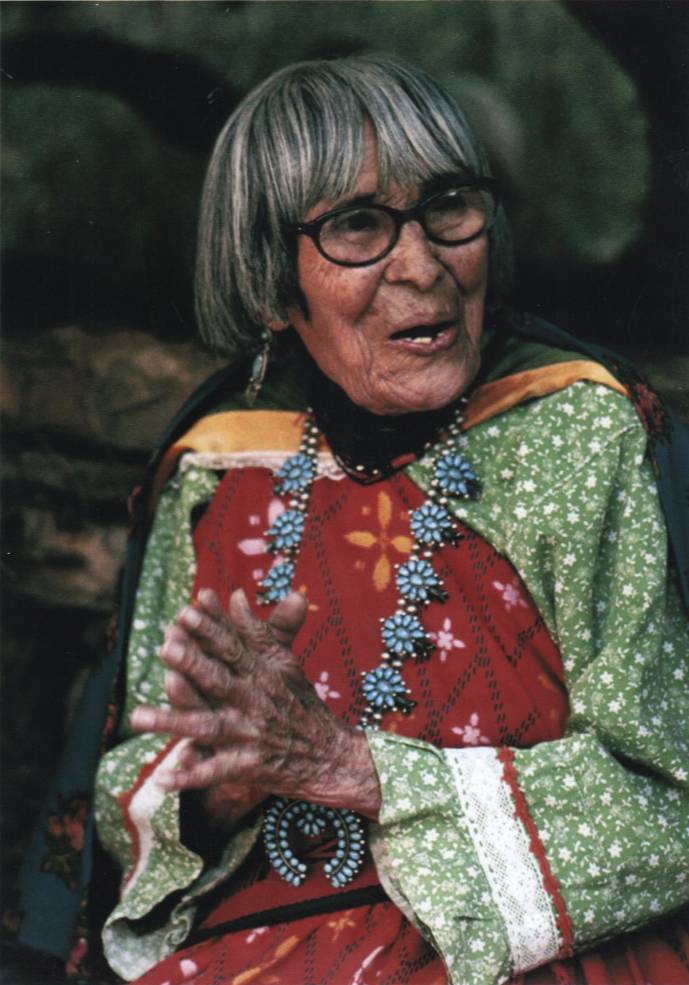 An elderly woman wearing a beaded necklace and traditional clothing.